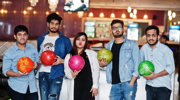 Five colleagues holding bowling balls at a team night out