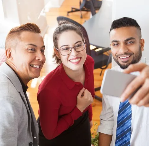 Three colleagues taking a selfie together in the office