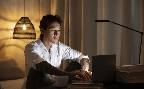 A man working on a laptop at home in the evening